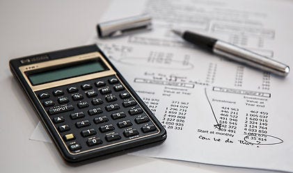 Classic Calculator laying on a desk with financial papers and a pen.