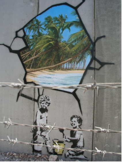 This mural depicts two young boys playing with buckets and shovels, like children creating sandcastles on a beach. The boys, one standing, the other kneeling, look back at the viewer, rendered in Banksy‘s typical black and white stencil aesthetic. Just above the boys, the artist has created the illusion of a broken section of the grey wall on which the mural was created. Through this false opening through the wall painted as a trompe-l’oeil, a photorealistic color image of a tropical beach.