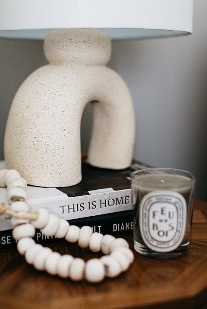 A contemporary lamp atop coffee table books and a scented candle