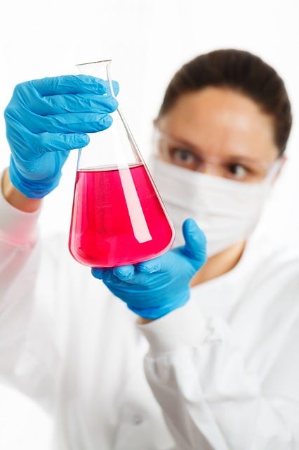 An image of a female chemist looking at a flask of chemicals