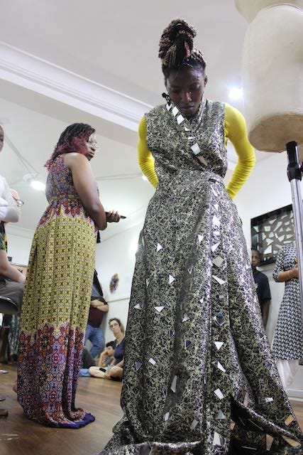 Woman wearing a dress made with shards of a mirror as people watch on