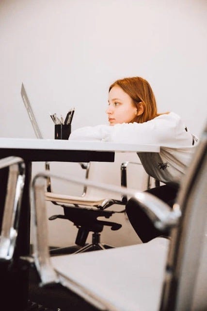 Woman sitting at a desk with her head balanced on her forearms