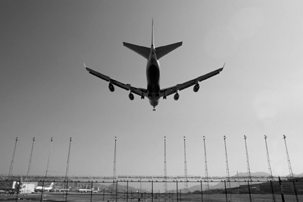 Under-fuselage shot of a 4-engined plane landing at an airport.