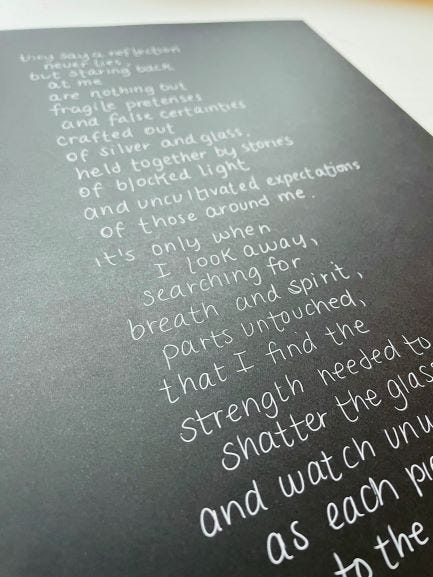 A handwritten copy of the poem that follows, written on black paper with a white pen.