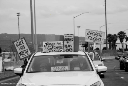 People in a car hold signs that say “Black Lives Matter,” “Justice for George Floyd,” & “Southeast Asians 4 Black Lives.”