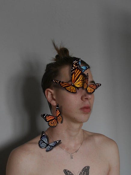 White girl with a butterfly tattoo and additional live butterflies on her face and neck