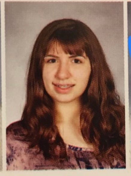 A photo of the author. A preteen with long wavy brown hair and choppy bangs. She’s smiling nervously, showing braces, and looking towards the camera. She’s wearing a tie dye purple shirt.