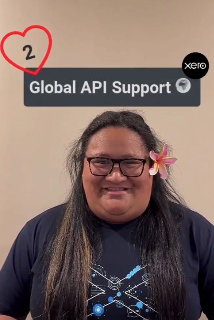 A woman with a a flower in her ear, with sign above her head saying ‘Global API Support’