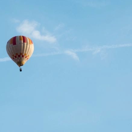 Image of a red and white hot-air balloon in the distance