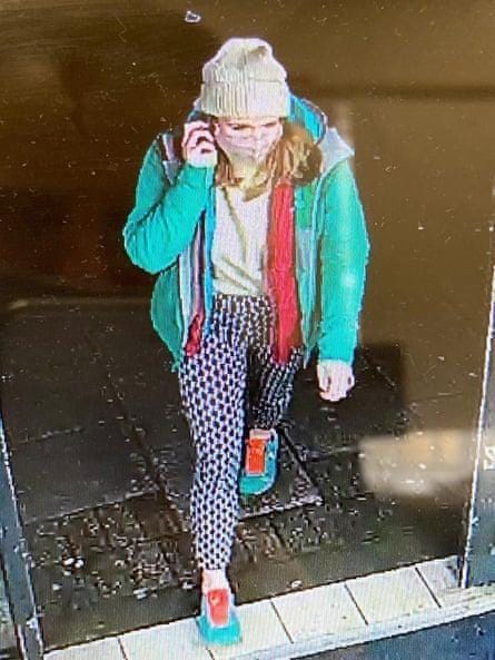 CCTV footage of a young blond woman walking while taking a phone call. She is captured wearing bright green and orange clothing.
