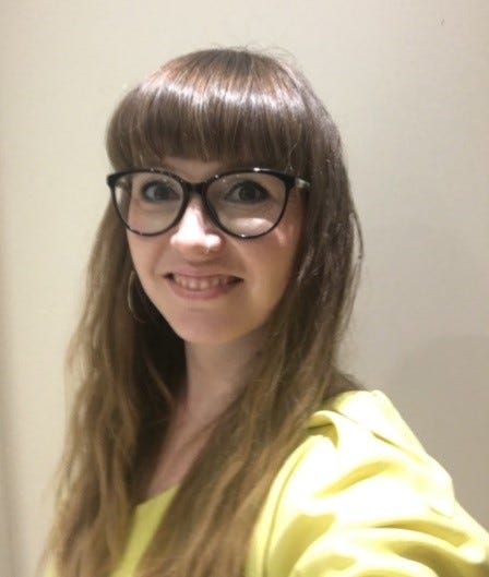 A headshot of Kelly, Head of Volunteering Transformation. Kelly is wearing glasses and a yellow top.