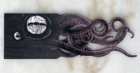 Bookmark that is dark purple with the image of a squid on it and one end of the bookmark is cut into swirling tentacle shapes.