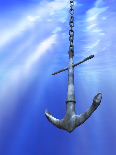 A grey anchor suspended in blue water, with light rays coming from above