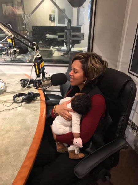 Dorcey Applyrs holds her infant while giving a radio interview.