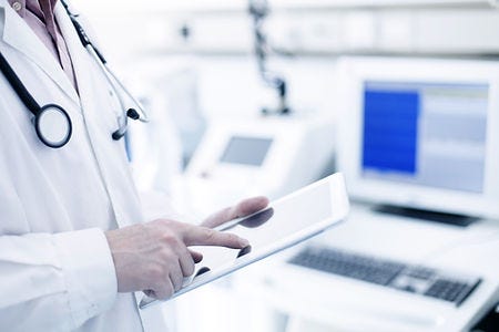 Doctor using digital tablet with medical equipment in the background