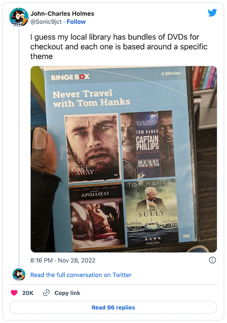 tweet from the link showing a DVD cover of a library “binge box” with the title “Never Travel With Tom Hanks” that includes four of his movies where something terrible happens to him including Sully and Apollo 13.
