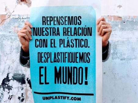 Someone is holding a blue sign about deplastification written in spanish