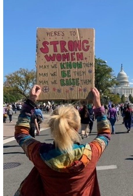 Sign reading “Here’s to strong women: may we know them, may we be them, may we raise them.”