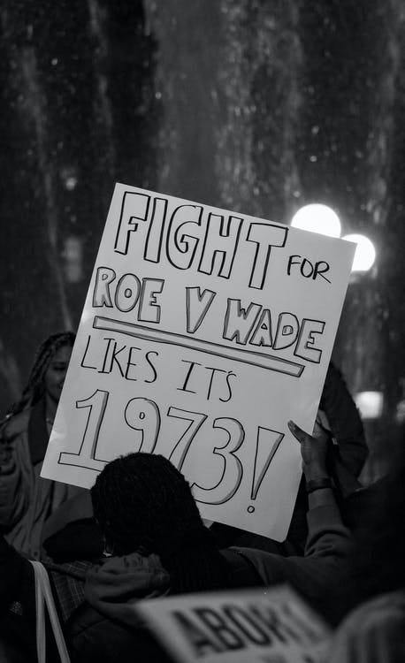 Black and white photo of a protest sign being held up at a protest: ‘Fight for Roe V Wade like it’s 1973!’