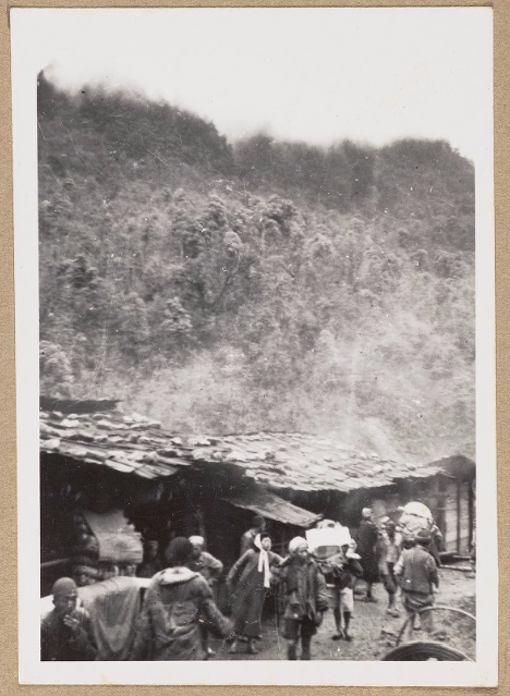Faded black and white photograph of the 10,000 Pass Way into Kangting, with villagers in the foreground.