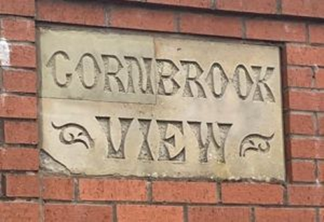 Engraved stone sign of ‘Cornbrook View’ surrounded by red-brick.