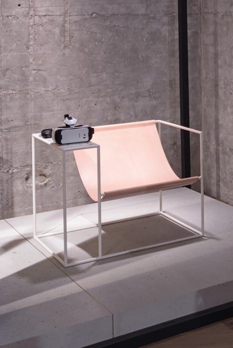 A cool designed armchair is connected to a table on which VR goggles are placed