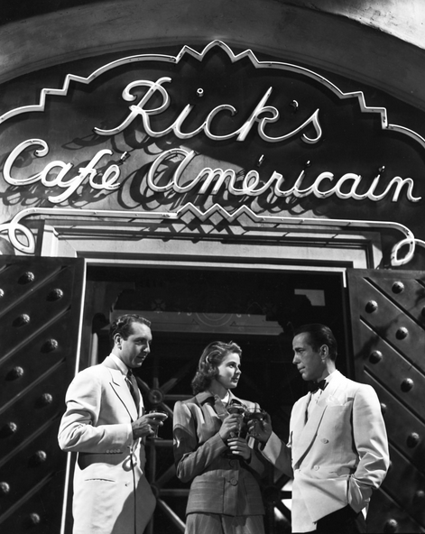 A man, a woman, and a man stand outside Rick’s Cafe Americain drinking cocktails