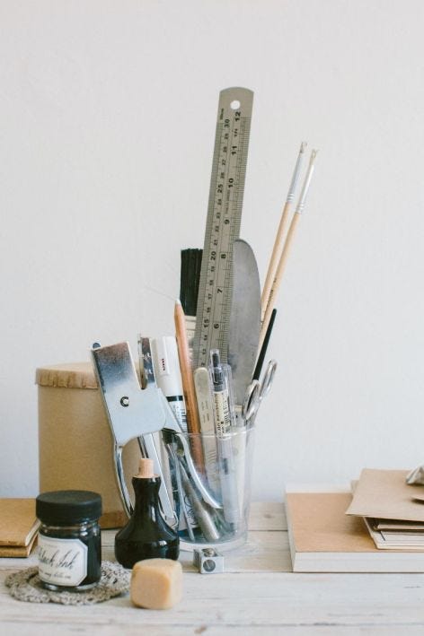 Table with cup filled with pens, rulers, staplers and other office supplies