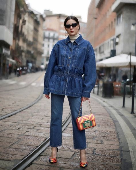 Девушка в джинсовой куртке, джинсах и водолазке.