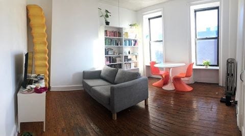 A wide show of the interior of an apartment living room, relatively normal-looking. In the corner, the fry is standing.