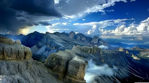 Panoramic view of the rugged Dolomite Mountains under a clear blue sky.