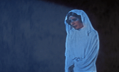 Holograma da Princesa Leia passando a mensagem para Luke Skywalker e Obi-wan Kenobi. Ela veste uma roupa, parecida com uma túnica, branca.
