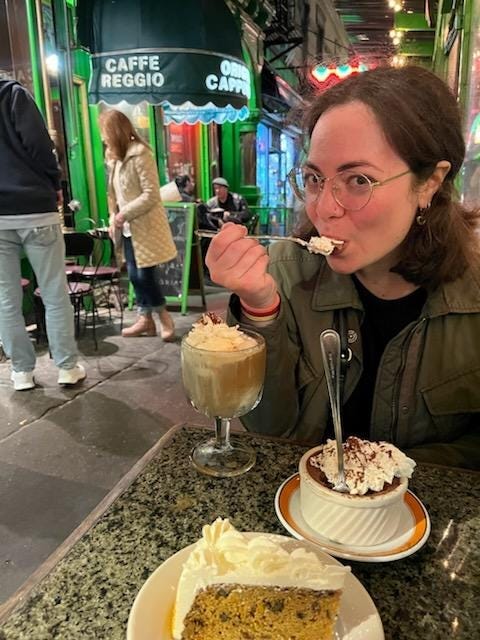The author, present day, eating a dessert with whipped cream on top