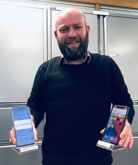 Photo of a person holding a Samsung S21 and iPhone 11 displaying emergency alerts