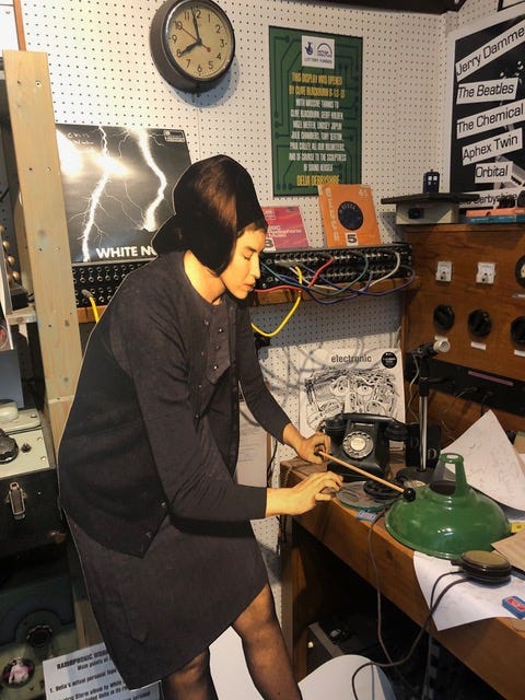 Cardboard cut out of Delia Derbyshire surrounded by instruments