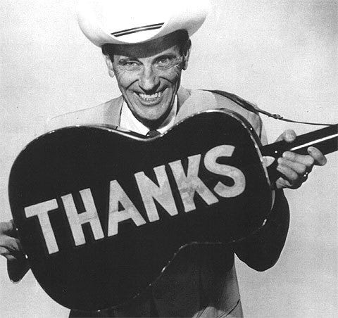 Black and white photo of Ernest Tubb holding a guitar that says Thanks in big block letters