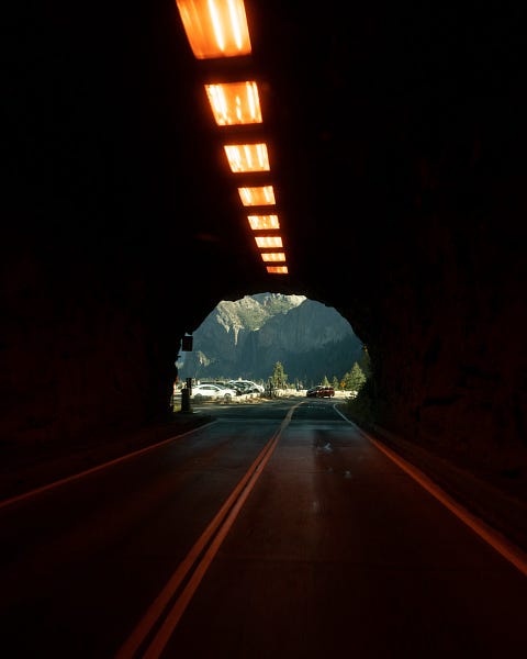 Lights leading through a tunnel to a landscape at the opening
