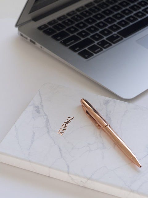 Image of a laptop, pen, and journal.