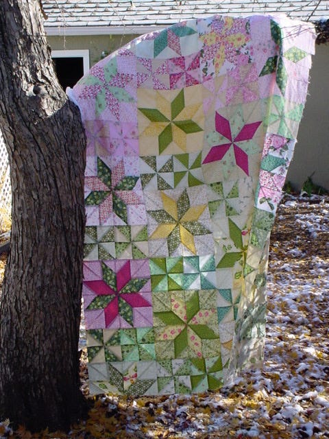 Image of a large piece of patchwork hanging from a tree branch