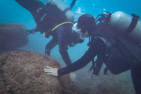 Two scuba divers looking at ruins