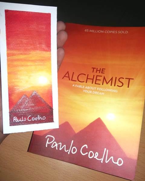 The picture contains a book and a bookmark of The Alchemist. The picture wants to promote reading