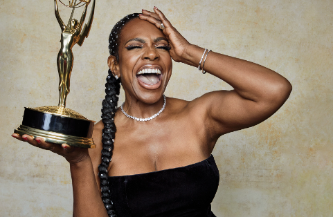 Photograph of Sheryl Lee Ralph holding her Emmy in one hand, and smiling with eyes clothes while her other hand brushes her forehead. Her expression is one of joy and excitement.