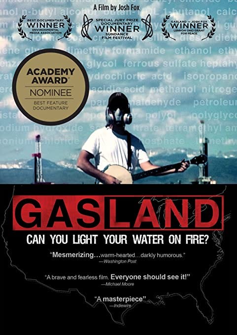 Film poster: man in gas-mask plays banjo in front of factory. Film title “Gasland: Can you light your water on fire?” imposed over map of USA.