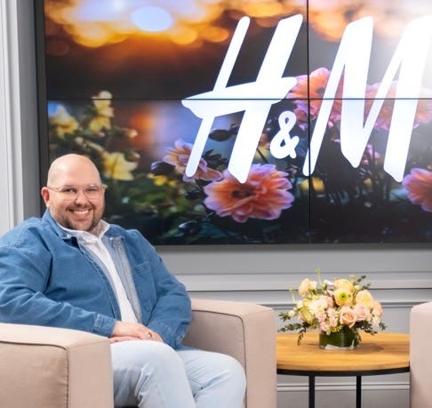 Chris Mikulski seated next to the H&M logo