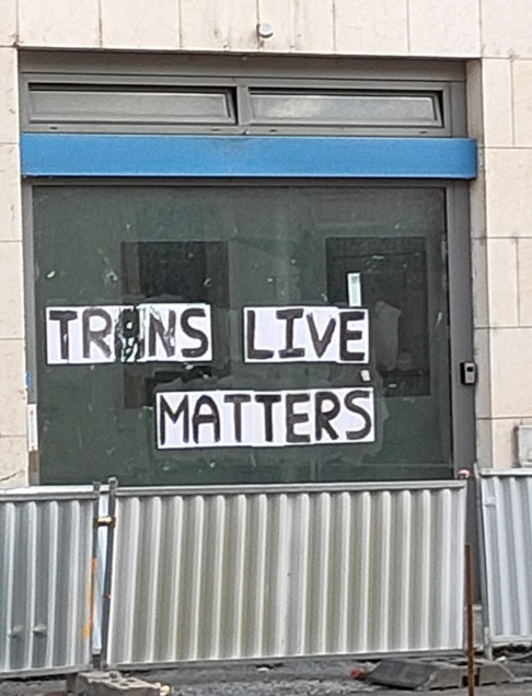 On a store window, there is an inscription “Trans live matters”