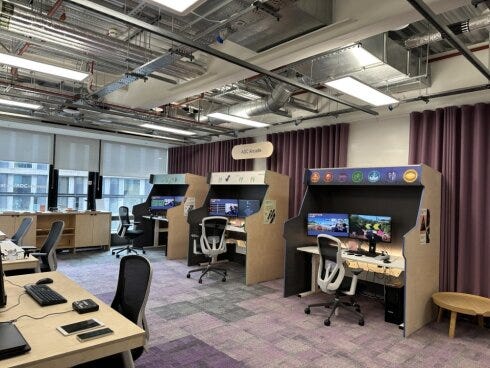 Room with 3 accessible game stations along the back wall with screens and technology like eye tracking or chin operated joy sticks.