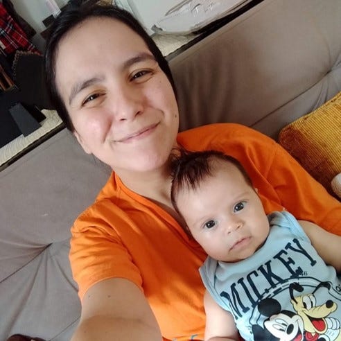 Uma mulher com seu filho, ainda bebê, no colo.