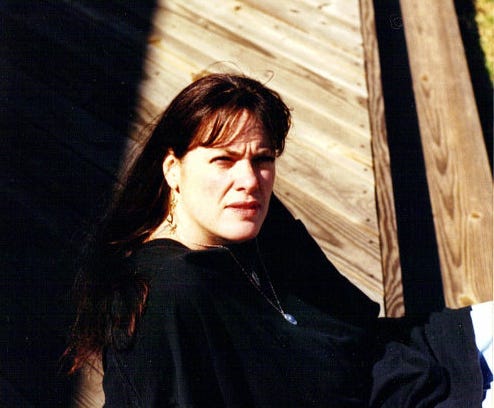 The author sitting on a deck with her face looking towards the camera.