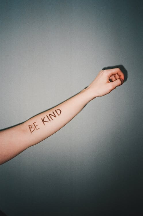 Someone’s hand with the written phrase of ‘BE KIND’