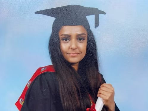 Sabina Ness, a young woman, poses for a picture in her graduation robes.
